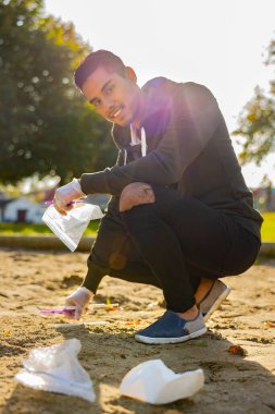 Parktaki çöpleri temizleyen gülümseyen adam.