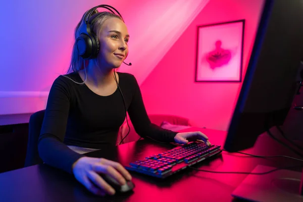 Feliz bonita rubia gamer chica jugando en línea video juego en su computadora personal . — Foto de Stock