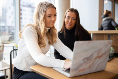 İki kız öğrenci şehirdeki kahve dükkanında proje üzerinde çalışıyor.