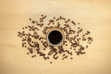 Masanın üzerinde kavrulmuş fasulye ve kahve fincanı var.