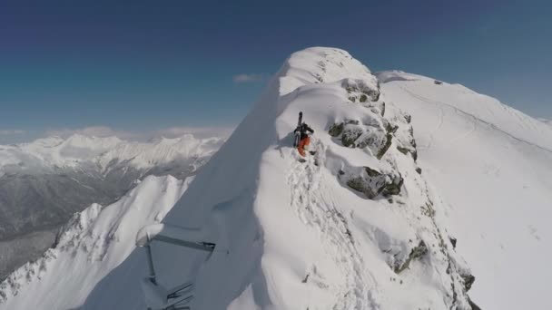 Skiër klimt bovenop een berg met sneeuw — Stockvideo