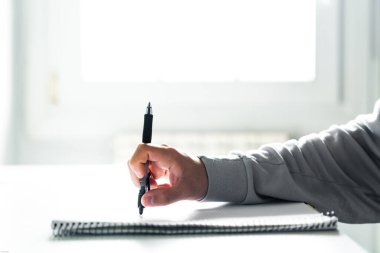 Öğrenci yatak odasındaki masada ödev yapıyor.