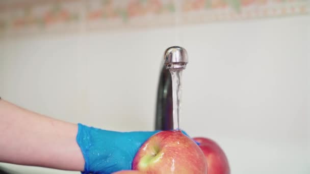 女人用蓝色乳胶手套用水洗红苹果 对水果进行消毒 以防止考拉病毒的传播 — 图库视频影像
