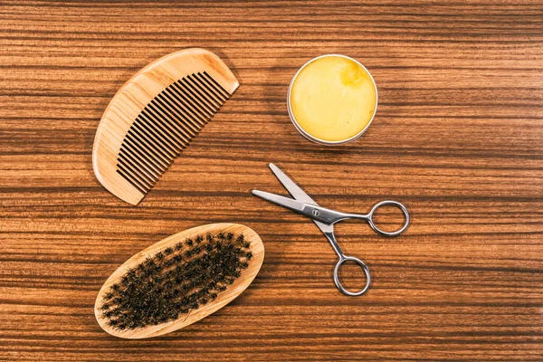 Hair Stylist Tools for Men\'s Haircut. Tools for cutting your hair and trimming your beard on a vintage wooden base.Modern wooden comb, beard brush, small metal scissors and wax.