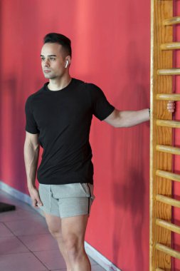 Kırmızı duvar spor salonundaki kaslı genç adam..