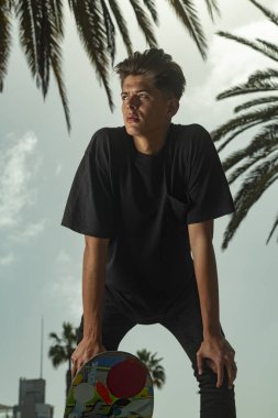 Arka planda palmiye ağaçları olan genç kaykaycının portresi.
