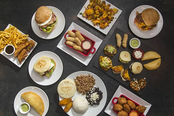 Table with Latin American food, arepa, tequeos, pabellon, cachapas. view from above.