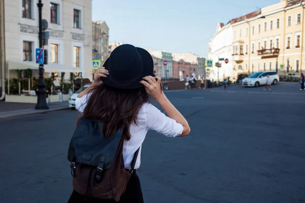 Junge Frau mit Hut, die in der Stadt spaziert, Rückansicht. Touristin genießt den Spaziergang. — Stockfoto