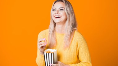 Genç, neşeli bir kadın gişe rekortmeni izliyor ve patlamış mısır yiyor..