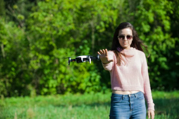Camina con un dron. Mujer joven con gafas negras lanza un dron de vuelo bajo. Llega a los aviones no tripulados de vuelo bajo, capturas . —  Fotos de Stock