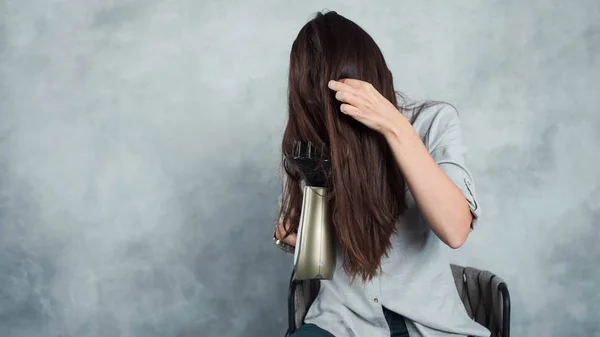 Μια νεαρή γυναίκα με μακριά σκούρα μαλλιά χρησιμοποιεί στεγνωτήρα μαλλιών για να στεγνώσει και να στυλ. Χτένισμα και περιποίηση μαλλιών, — Φωτογραφία Αρχείου