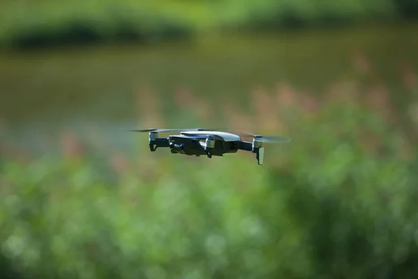 Drone a quattro eliche che vola in natura contro la natura verde La manovra. Sfondo sfocato . — Foto Stock