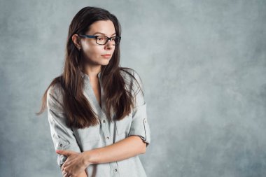 Gri gömlekli başarılı, kendine güveni tam genç bir kadın dokusu gri bir duvara karşı..