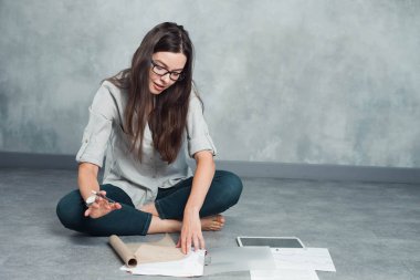 Genç serbest çalışan kadın ve girişimci yerde oturan bir proje üzerinde çalışıyor..