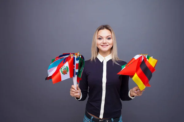 Χαρούμενη νεαρή γυναίκα με ένα μεγάλο σύνολο σημαιών από διαφορετικές χώρες του κόσμου — Φωτογραφία Αρχείου