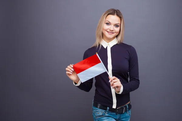 Inmigración y el estudio de lenguas extranjeras, concepto. Una joven sonriente con una bandera de Mónaco en la mano. — Foto de Stock