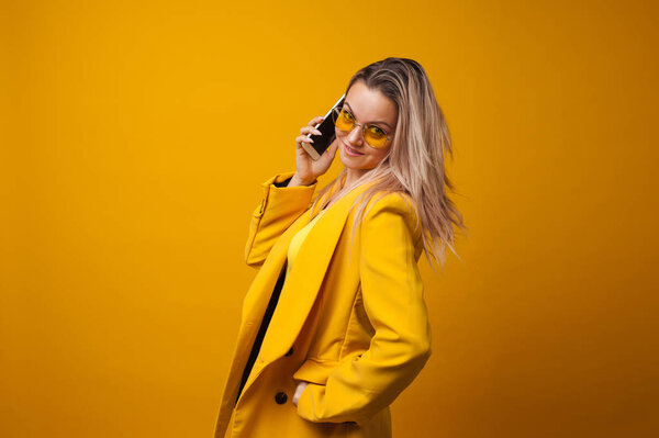 Stylish positive young woman on yellow background, copy space.