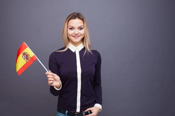 Inmigración y el estudio de lenguas extranjeras, concepto. Una joven sonriente con una bandera de España en la mano. —  Fotos de Stock