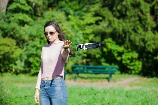 Gå med en drönare. Ung kvinna i svarta glasögon lanserar en låg flygande drönare. Når ut till låg flygande drönare, fångster. — Stockfoto