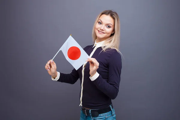 이민 과 외국어 공부, 개념. 손에 일본 국기를 들고 미소를 짓고 있는 젊은 여자. — 스톡 사진