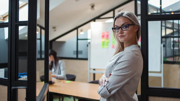 Молодая уверенная деловая женщина в очках на фоне рабочего пространства . — стоковое фото