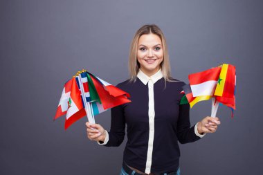 Dünyanın farklı ülkelerinden bayrakları olan neşeli genç bir kadın.