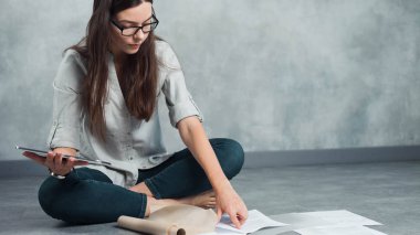 Genç serbest çalışan kadın ve girişimci yerde oturan bir proje üzerinde çalışıyor..