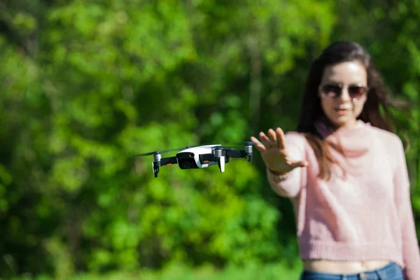 Cammina con un drone. Giovane donna in occhiali neri lancia un drone a basso volo. Raggiunge a basso drone volante, catture . — Foto Stock