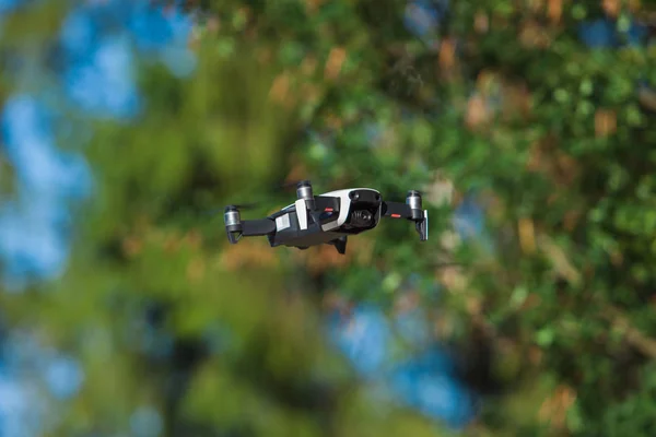 Fyrpropeller drönare flyger i naturen mot den gröna naturen Manöver. suddig bakgrund. — Stockfoto