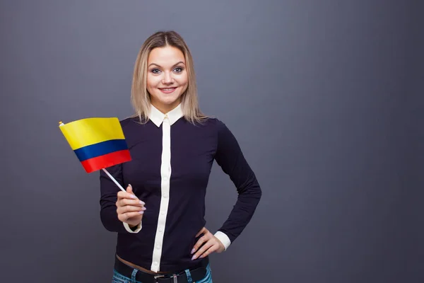 Inmigración y el estudio de lenguas extranjeras, concepto. Una joven sonriente con una bandera de Colombia en la mano . — Foto de Stock