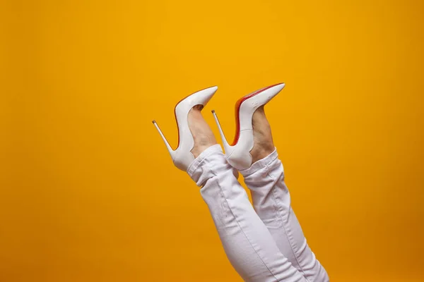 Női láb gyönyörű fehér tűsarkú cipő, sárga háttér másolási hely. — Stock Fotó