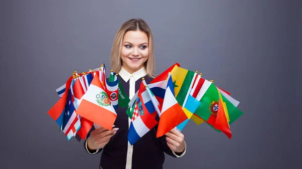 Wesoła młoda kobieta z dużym zestawem flag z różnych krajów świata — Zdjęcie stockowe