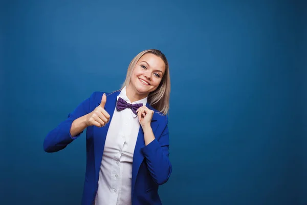 Divertida dama de negocios con chaqueta azul y pajarita púrpura. salta de alegría y da un pulgar hacia arriba . — Foto de Stock