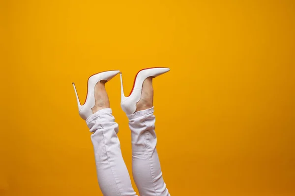 Női láb gyönyörű fehér tűsarkú cipő, sárga háttér másolási hely. — Stock Fotó