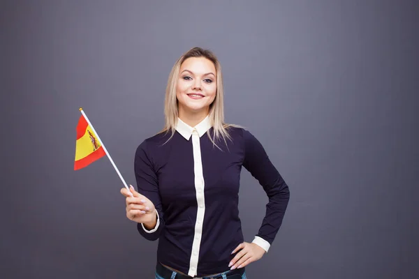 Imigrace a studium cizích jazyků, koncepce. Mladá usměvavá žena s vlajkou Španělska v ruce. — Stock fotografie