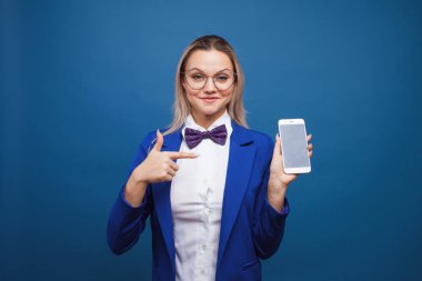 Şık mavi ceketli ve papyonlu sevimli ve komik iş kadını akıllı telefon kullanıyor..