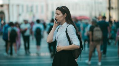 Büyük şehrin sokaklarında kalabalığın içinde olan kız. Şehirde genç bir kadın cep telefonu kullanıyor.