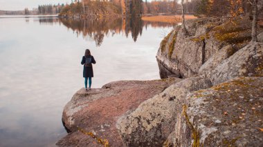 Gölün kıyısında bir kadın tek başına duruyor. Düşüncelilik ve meditasyon.