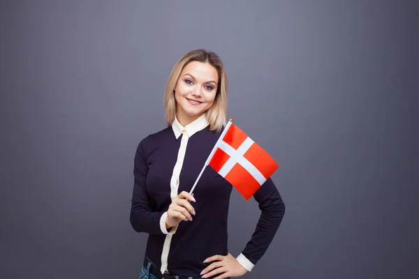 Einwanderung und Fremdsprachenstudium, Konzept. eine junge lächelnde Frau mit einer dänischen Flagge in der Hand. — Stockfoto