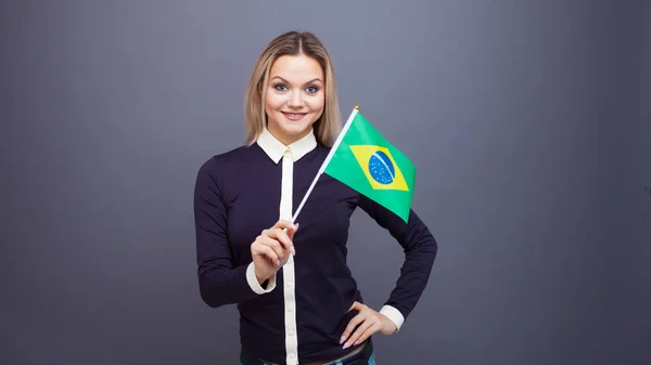 Immigratie en de studie van vreemde talen, concept. Een jonge glimlachende vrouw met een Braziliaanse vlag in haar hand. — Stockfoto