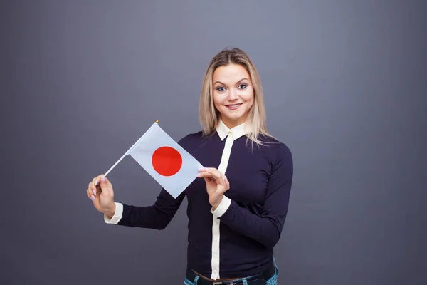 Inmigración y el estudio de lenguas extranjeras, concepto. Una joven sonriente con una bandera de Japón en la mano . — Foto de Stock