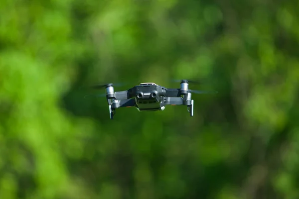 Drone de cuatro hélices volando en la naturaleza contra la naturaleza verde La maniobra. Fondo borroso . —  Fotos de Stock