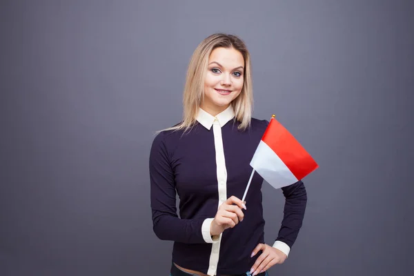 Einwanderung und Fremdsprachenstudium, Konzept. Eine junge lächelnde Frau mit einer Monaco-Fahne in der Hand. — Stockfoto