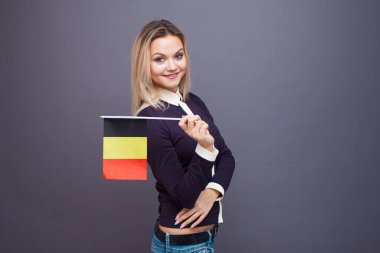 Göçmenlik ve yabancı dil eğitimi, konsept. Elinde Belçika bayrağı olan gülümseyen genç bir kadın..