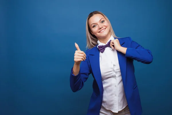 Divertida dama de negocios con chaqueta azul y pajarita púrpura. salta de alegría y da un pulgar hacia arriba . — Foto de Stock