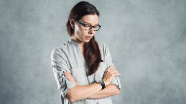 Gri gömlekli başarılı, kendine güveni tam genç bir kadın dokusu gri bir duvara karşı..