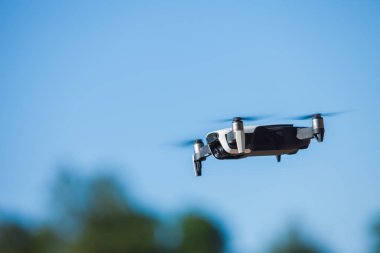 Four-propeller drone flying in nature against the blue sky. The maneuver.