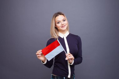 Göçmenlik ve yabancı dil eğitimi, konsept. Elinde Monako bayrağı olan gülümseyen genç bir kadın..