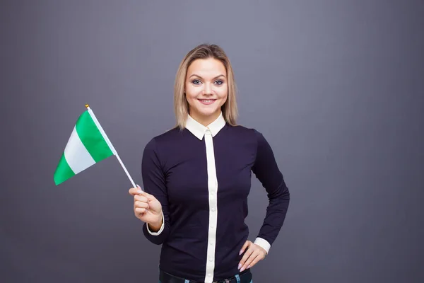 Imigrace a studium cizích jazyků, koncepce. Mladá usměvavá žena s nigerijskou vlajkou v ruce. — Stock fotografie