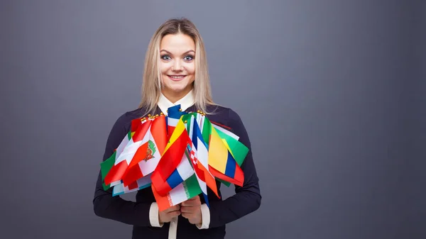 Joven alegre con un gran conjunto de banderas de diferentes países del mundo — Foto de Stock